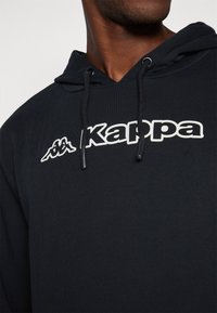 Felpa blu marina realizzata in tessuto morbido, con un grande logo bianco "Kappa" e dettagli con cordoncino sul cappuccio.