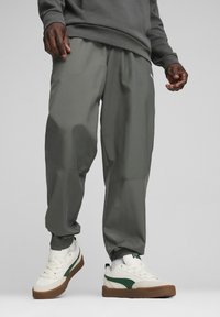 Szare sportowe dresy o luźnym kroju, z elastycznymi ści�ągaczami i subtelnym połyskiem; zestawione z białymi i zielonymi trampkami o niskim profilu.