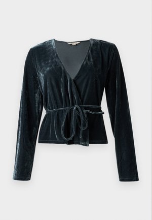 Velvet innpakningstopp i mørkegrønn, med dyp V-hals, lange ermer og belte i livet. Glatt tekstur med lett glans.