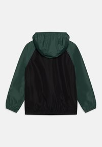 Hooded jacket with black body and dark green sleeves, made of smooth, lightweight material. Features elastic cuffs and a gathered hood.