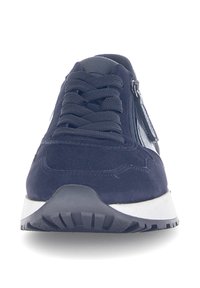 Marineblauwe suède sneakers met textuurveters en een zijritsdetail, voorzien van een witte tussenzool en een zwarte rubberen zool voor grip.