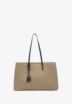 Beżowa torba na ramię z materiału z długimi ciemnymi, teksturowanymi rączkami, w kształcie prostokąta, z dekoracyjną zawieszką i srebrnymi elementami. Brak wyraźnych wzorów.