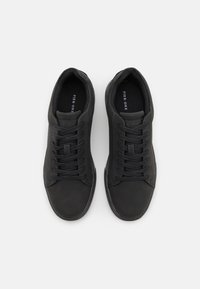 Svarta lädersneakers med en slät textur, rund tå, platta snören och minimalistisk design. Logotyp synlig på den inre fodret.