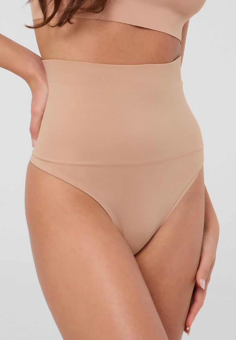 Braghe in shapewear a vita alta color nude realizzate in tessuto liscio e elastico, con un design senza cuciture per un fit confortevole.