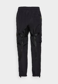 Zwarte cargo broek van een glad, lichtgewicht materiaal. Bevat verstelbare banden, meerdere zakken en elastische boorden bij de enkels.