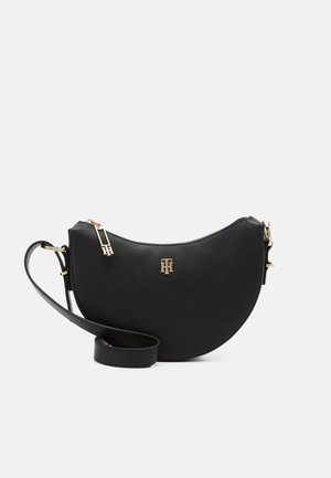 Black leather crossbody bag with a half-moon shape, featuring a gold-tone zipper and logo, and an adjustable strap. Textured surface.