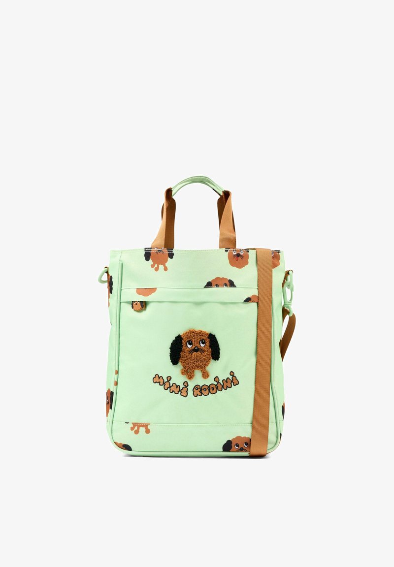 Borsa a mano verde chiaro con facce di cane marrone ovunque, tasca frontale, manici marroni e tracolla, testo "Mini Rodini" sotto il disegno centrale del cane.