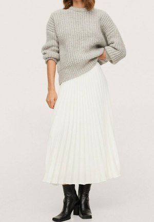 Suéter gris de punto con cuello redondo, combinado con una falda midi blanca plisada y botines negros de tacón.