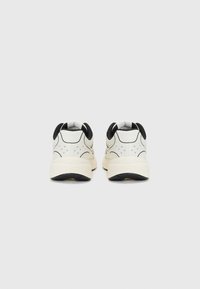 White sneakers with black accents, textured mesh upper, smooth rubber sole, and subtle design details on the heel. Rear view shown.