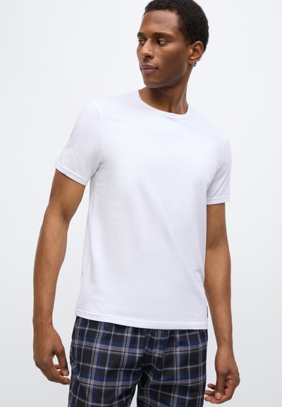 Balta īsroku kokvilnas T-krekls ar apaļu izgriezumu kaklam. Kombinēts ar zilām un melnām rūtainām pidžamas biksēm.