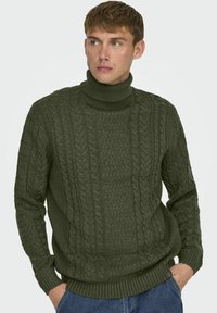 Suéter de punto verde oliva con cuello alto. Presenta patrones de cable texturizados y de canalé, mangas largas y un dobladillo ajustado.