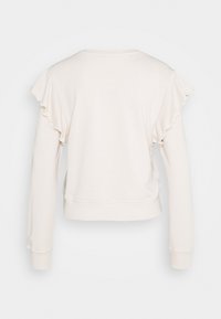 Top largo de manga larga en beige claro con acentos de hombros con volantes, cuello redondo y cintura ajustada, confeccionado en un tejido suave y liso.
