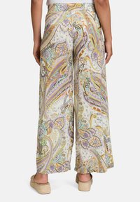 Kalhoty s širokým střihem s vícebarevným paisley vzorem na světle krémovém pozadí, s hladkou strukturou tkaniny a vysokým pasem.