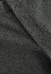 Tissu gris foncé au toucher lisse, présentant un pli diagonal et des détails de couture. Le matériau semble durable avec un léger brillant.