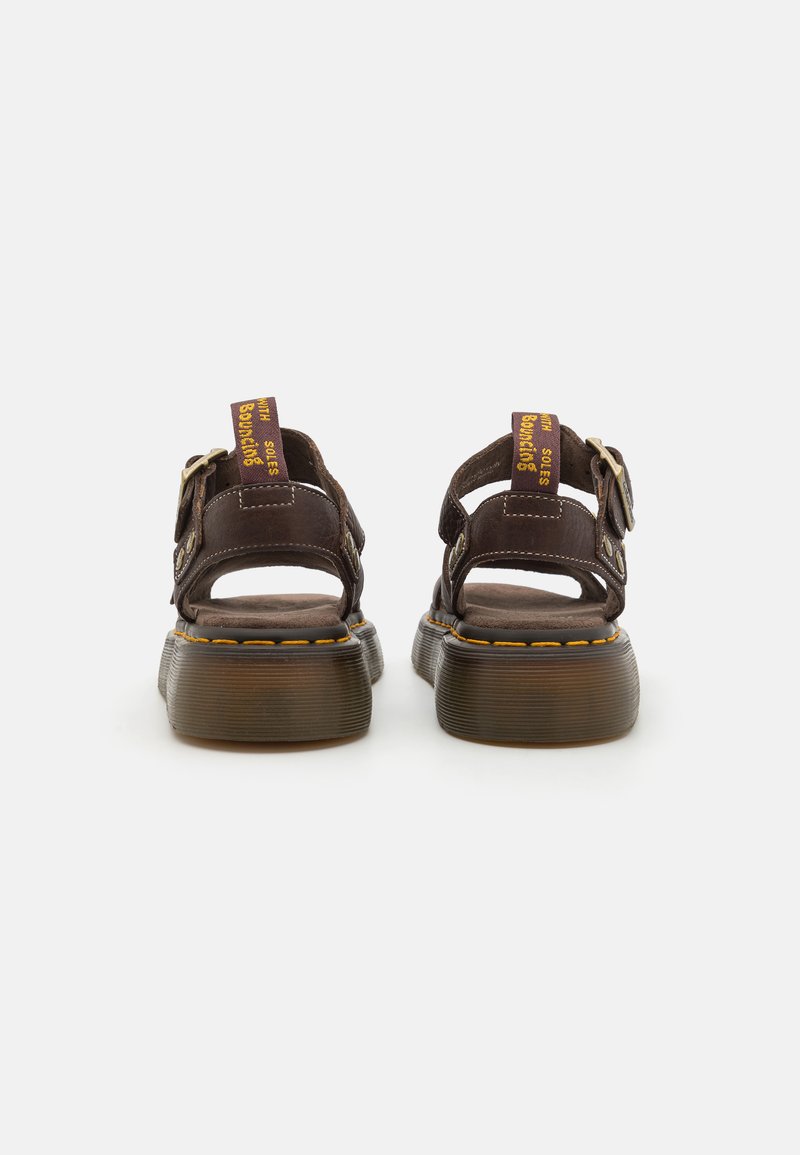 Sandali in pelle marrone con retro aperto, cinturini regolabili, fibbie rotonde e cuciture gialle in evidenza sulle suole in gomma.