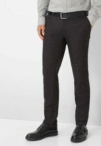 Dunkelbraune, maßgeschneiderte Hosen aus strukturiertem Stoff, mit schlanker Passform, seitlichen Taschen und getragen mit schwarzen Schuhen und einem Gürtel.