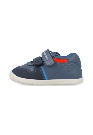 Zapato azul y marino hecho de materiales sintéticos, con tiras de Velcro, suela blanca y acentos en rojo y azul. Logo de biomecánica en el talón.