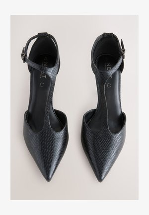 Schwarze spitze Pumps aus strukturiertem Kunstleder. Verfügen über ein offenes Design mit Knöchelriemen und einem niedrigen Ausschnitt. Glattes Innenfutter.