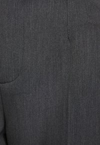 Tmavě šedá textilie s jemně tkanou strukturou, obsahující viditelné švy a jemné variace vzoru.