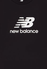 Zwart katoenen t-shirt met een groot wit "NB" logo en de tekst "new balance" eronder in een strakke, moderne lettertype.