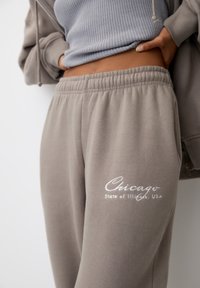 Grå sweatpants med elastisk midja, prydda med "Chicago State of Illinois, USA" broderat i vitt. Mjuk tygkvalitet med en avslappnad passform.