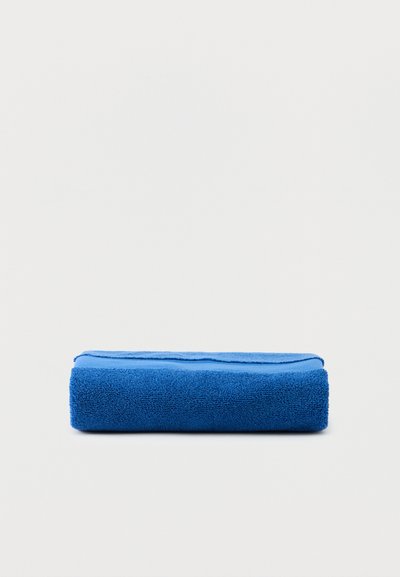 Φωτεινή μπλε πετσέτα διπλωμένη προσεκτικά πάνω σε απλή λευκή επιφάνεια.