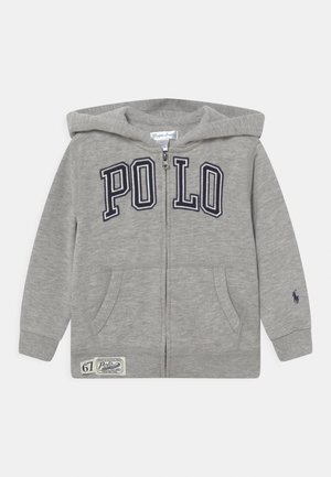 Sweat à capuche gris clair zippé, avec capuche, poches avant, inscription "POLO" sur la poitrine et petit logo brodé sur le poignet de la manche gauche.