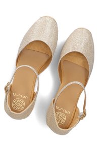 Beige textiel schoenen met een glanzende afwerking, open teen, lage hak en enkelband met een gesp. Zachte binnenkant en gestructureerde zool.