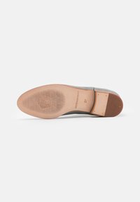 Zapato de ante gris con punta lisa y redondeada y suela de cuero marrón; presenta un patrón texturizado y un logo grabado en la suela. Talla 37.
