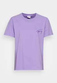 T-shirt di cotone lavanda con maniche corte, colletto rotondo e logo ricamato in viola sul lato sinistro del petto. Texture liscia e vestibilità casual.