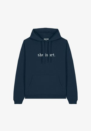 Tengerészkék kapucnis pulóver elülső zsebbel és húzózsinórral. A "she is art." szöveg fehér színben van nyomtatva a mellkas területén. Puha szövettextúra.