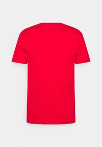 Camiseta de algodón roja con mangas cortas, cuello redondo y un diseño trasero liso, que presenta una textura suave sin patrones ni acentos.
