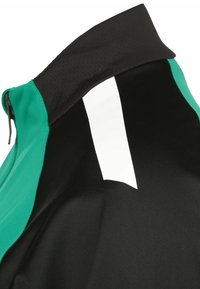 Zwarte en te groene fietsjas met een hoge kraag, voorzien van een witte reflecterende streep op de achterkant en een gestructureerde stof voor ventilatie.