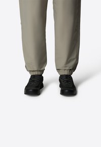 Ljust grå, elastiska midjebyxor med samlade anklar och fickor, matchade med svarta snörskor med gummisulor och texturerad ovandel.