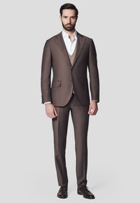 Brąski garnitur szyty na miarę z teksturowanym kamizelką, dopasowaną marynarką i pasującymi spodniami. Biała koszula pod spodem, brązowe skórzane buty.