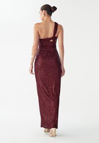 Bordo toonilise ühekõlalise sädelevast litritest õhtukleit, millel on keha järgiv siluett ja vöökohal lõhik, pikk seelik ning sile kangapind.