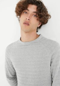 Suéter texturizado gris claro con un diseño de canalé, con cuello redondo y mangas raglán, hecho de un material suave.