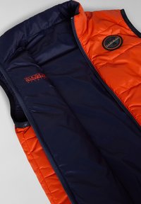 Gilet imbottito con una parte superiore arancione vivace e una parte inferiore blu navy. Presenta cuciture bordate, una zip completa e un'applicazione rotonda con logo.