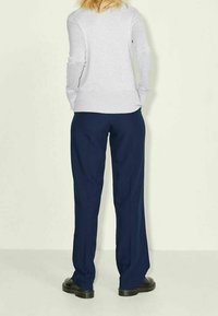 Grå långärmad skjorta och marinblå byxor med vida ben, kombinerat med svarta skor. Enkel design, utan mönster eller synliga fästen.