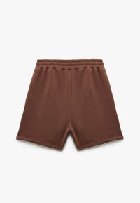 Pantalones cortos de algodón marrón con una cintura elástica, que presentan un diseño simple y una textura suave. Sin patrones visibles ni acentos de hardware.
