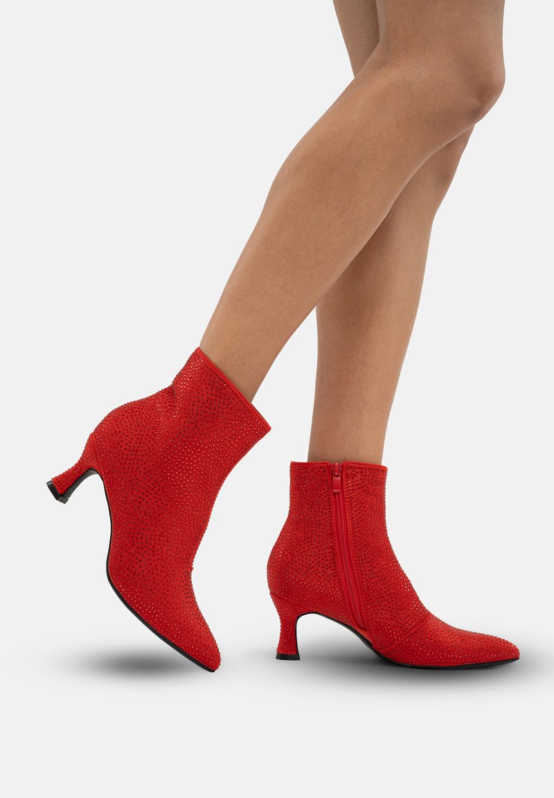 Botines rojos con una superficie texturizada, adornados con rhinestones. Cuentan con una cremallera lateral y un tacón de tipo kitten moderado.