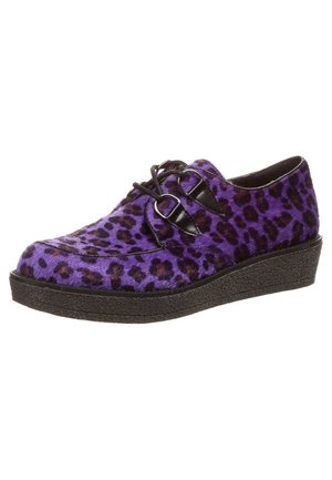 Mocassin imprimé léopard violet et noir avec des brides à boucle noires et une semelle plateforme noire texturée.