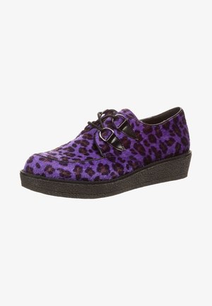 Mocassin imprimé léopard violet et noir avec des brides à boucle noires et une semelle plateforme noire texturée.