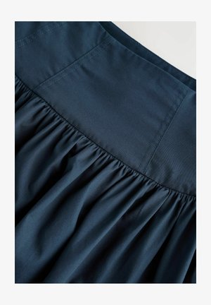 Syvän sininen kerätty hame, jossa on sileä vyötärö ja näkyviä ompeluja. Hameessa on pehmeä, teksturoitu kangas, joka luo virtaavan ilmeen.