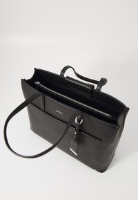 Sac cabas en cuir noir avec deux poignées, poche avant, compartiment principal zippé et étiquette en cuir suspendue, présenté sur fond blanc.