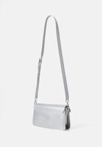 Sac bandoulière en cuir argenté, de forme rectangulaire fine, avec un rabat plat et une sangle amovible et ajustable.