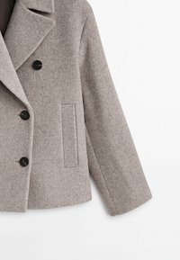 Manteau en laine gris avec trois boutons noirs, un large col à revers et une seule poche verticale sur le côté droit.