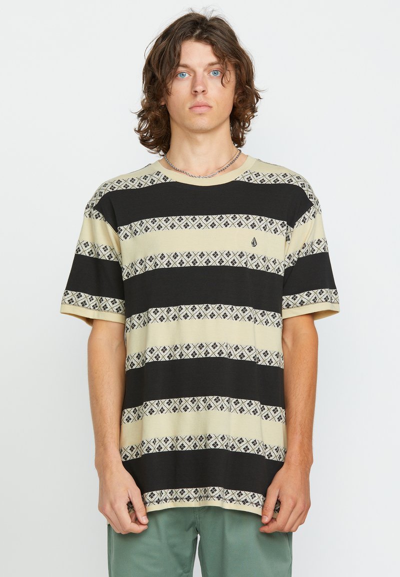Kortærmet t-shirt i beige med sorte vandrette striber og mønstrede detaljer. Har rund hals og et lille logo på brystet.