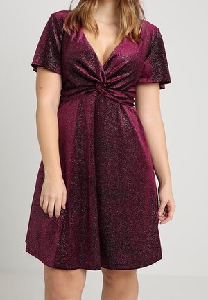 Sukienka z krótkim rękawem i głębokim dekoltem w kształcie litery V, wykonana z błyszczącej bordowej tkaniny. Posiada wiązany z przodu detal oraz rozkloszowaną spódnicę do kolan.