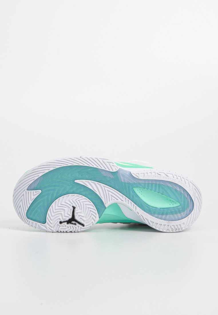 Suela de zapatilla blanca y verde azulado con un dibujo texturizado y el logo negro de Jumpman visible cerca del talón, sobre un fondo blanco liso.